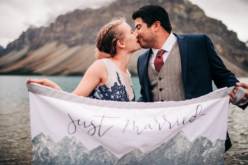 newly eloped adventure couple kissing and holds just married sign